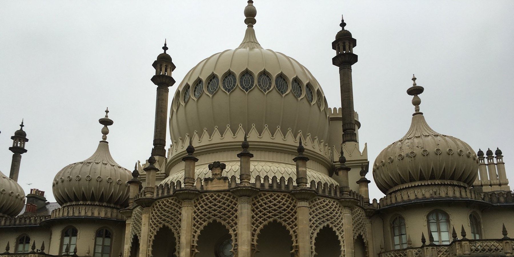 Exterior view of the Royal Pavilion in Brighton, England, with ornate domes and columns under a gray sky.