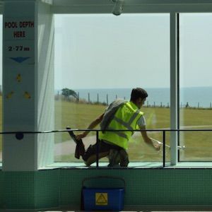 Man cleaning inside of windows looking out over sussex coastline with Traditional window cleaning squeegee technique