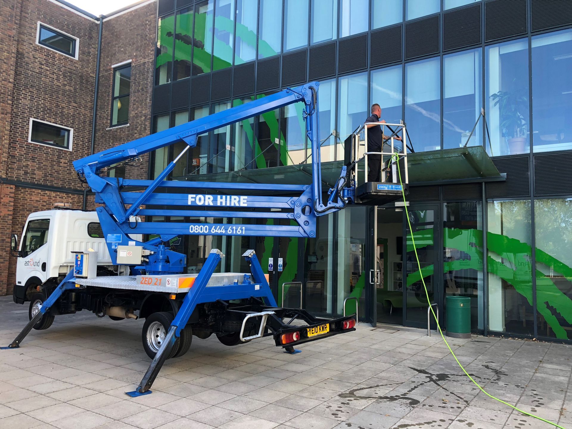 Blue truck-mounted lift with a worker near a building;
