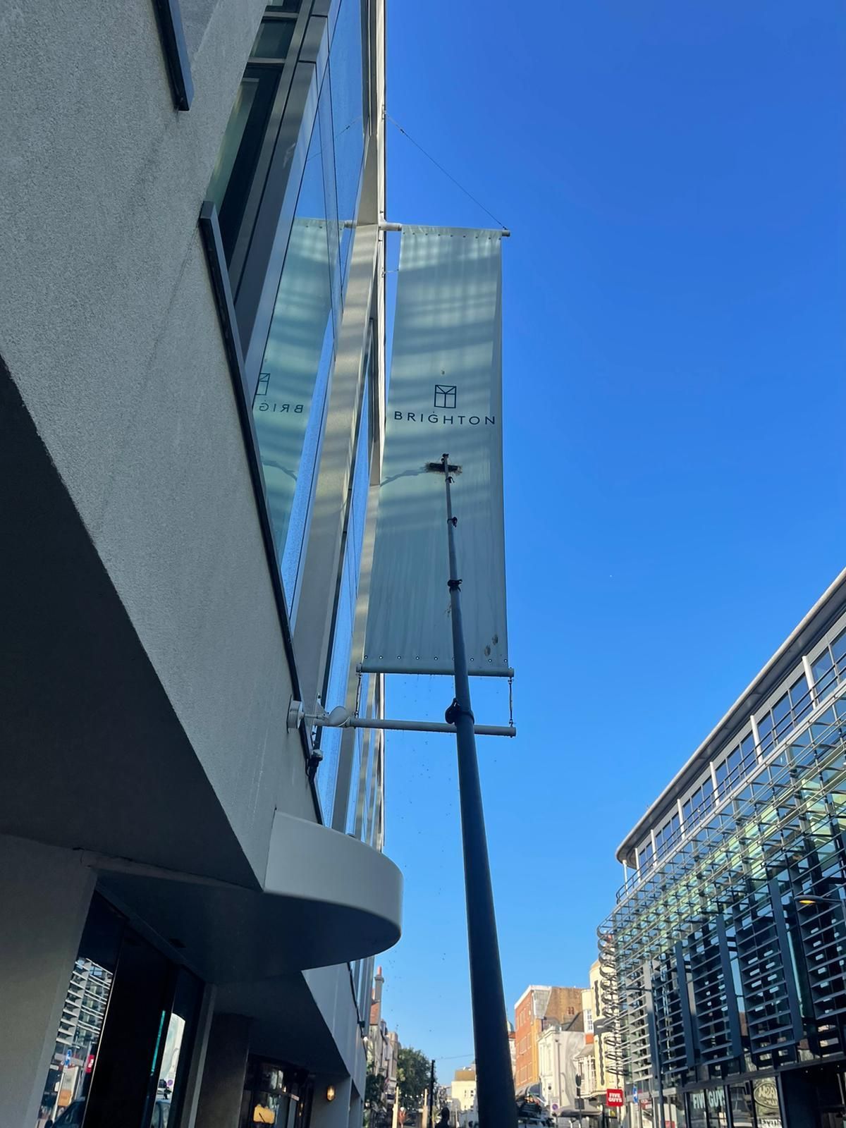 Tall building with banners on a sunny day; street below.