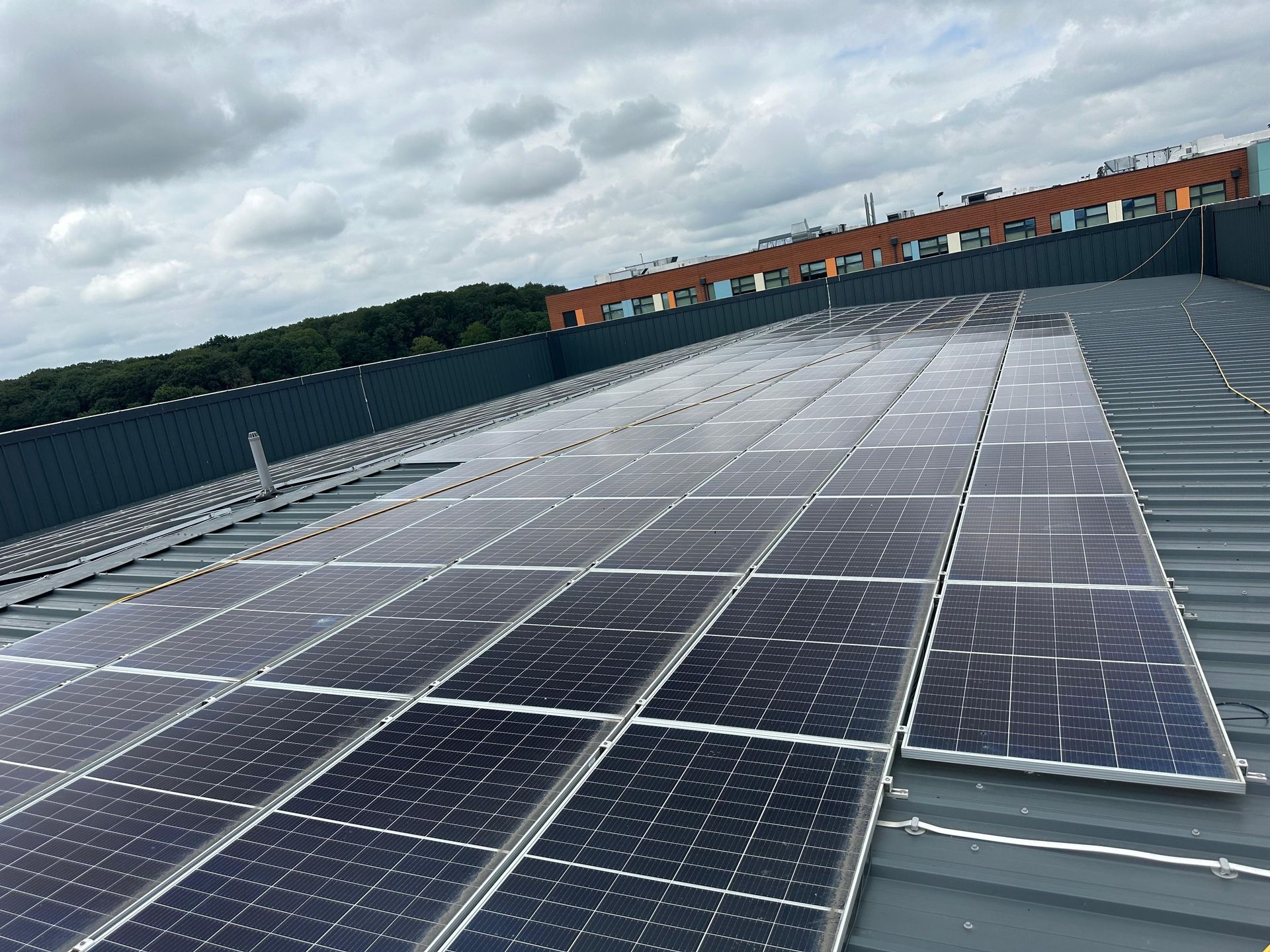 Solar panels on a sloped roof under a cloudy sky, possibly generating electricity.