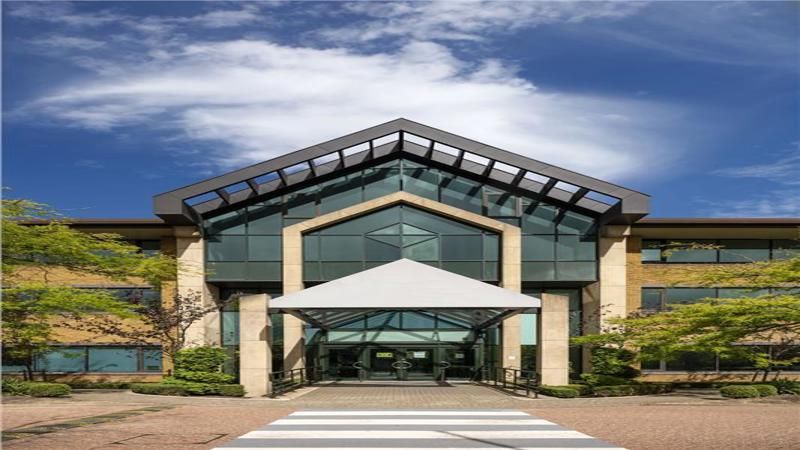 Office building with glass facade, canopy entrance, and blue sky.