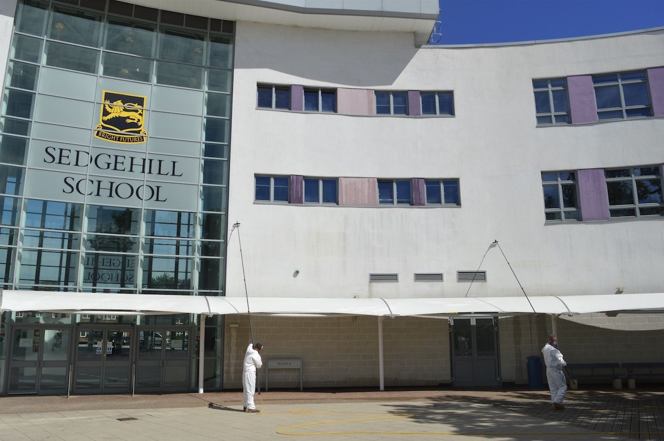Two people in hazmat suits spraying the entrance of Setchehill School.