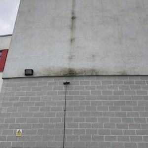 Grey rendered wall showing pollution soiling before professional render cleaning