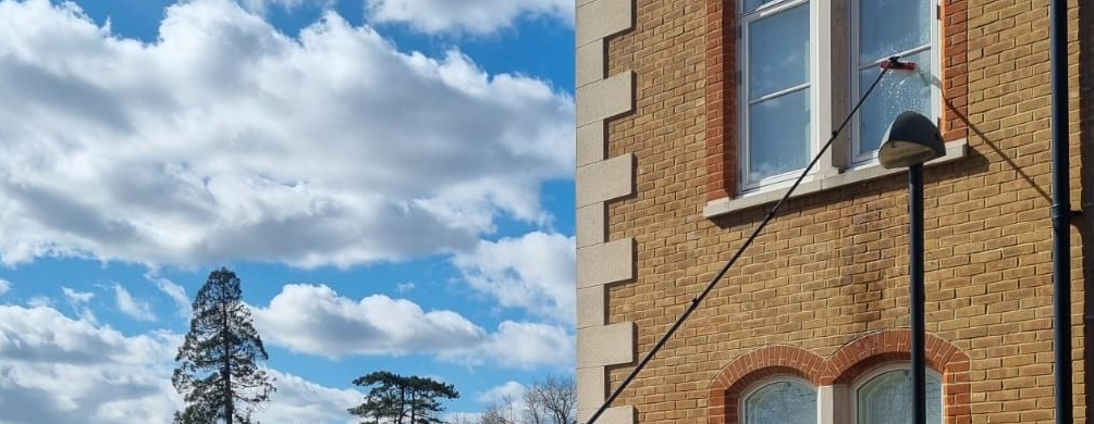 Astound Cleaning Group window cleaner using a pure-water pole on a residential home — professional home window cleaning in Sussex & South London