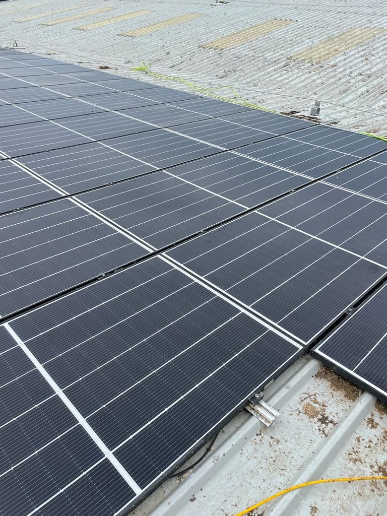 Solar panels on a rooftop, arranged in rows. Gray panels and white lines, with a gray rooftop.