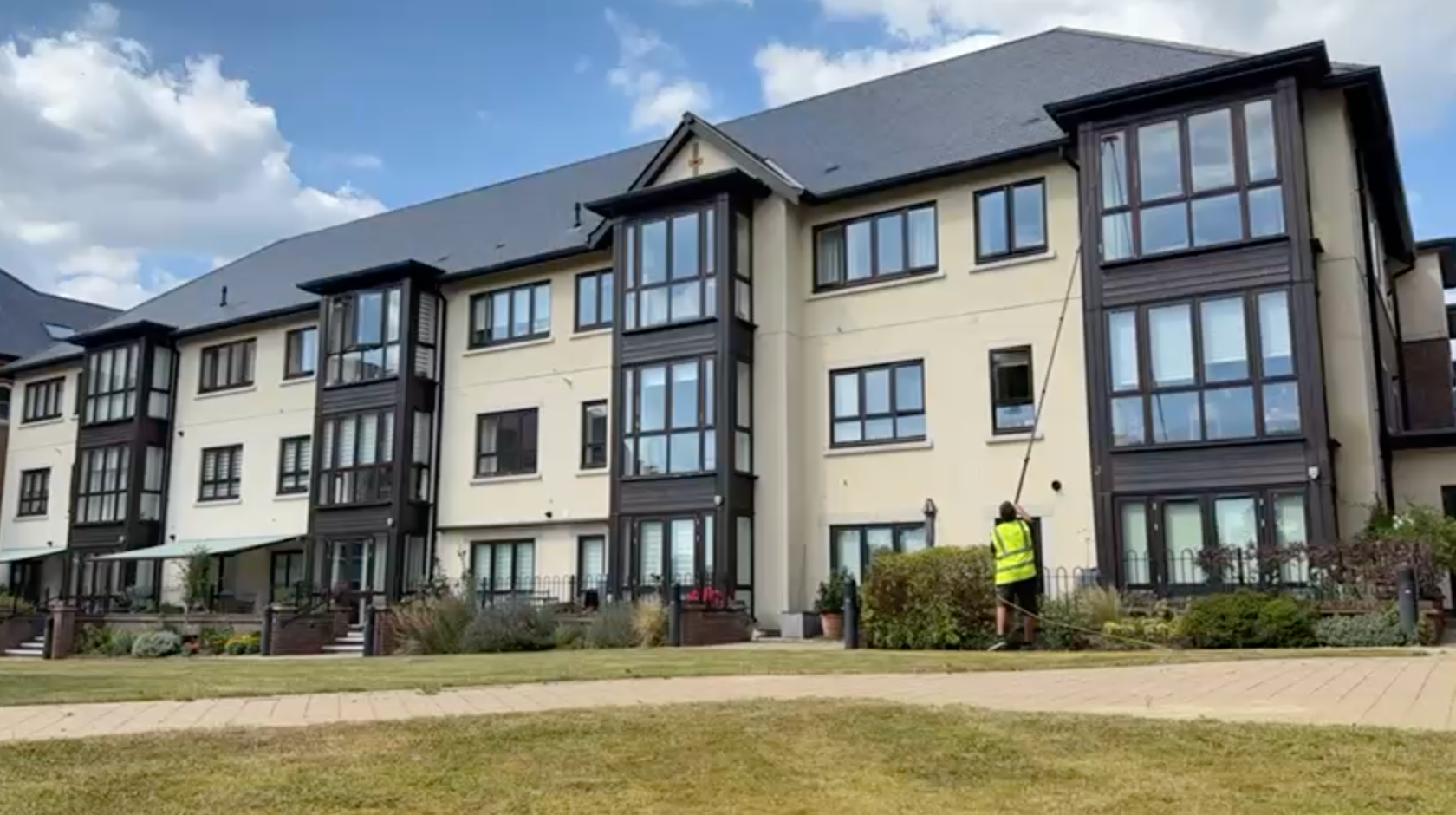Water fed pole window cleaning in progress on a multi-storey residential apartment block with an ope