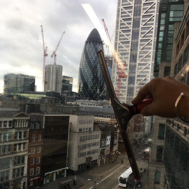Traditional window cleaning squeegee cleaning glass with London skyline in background