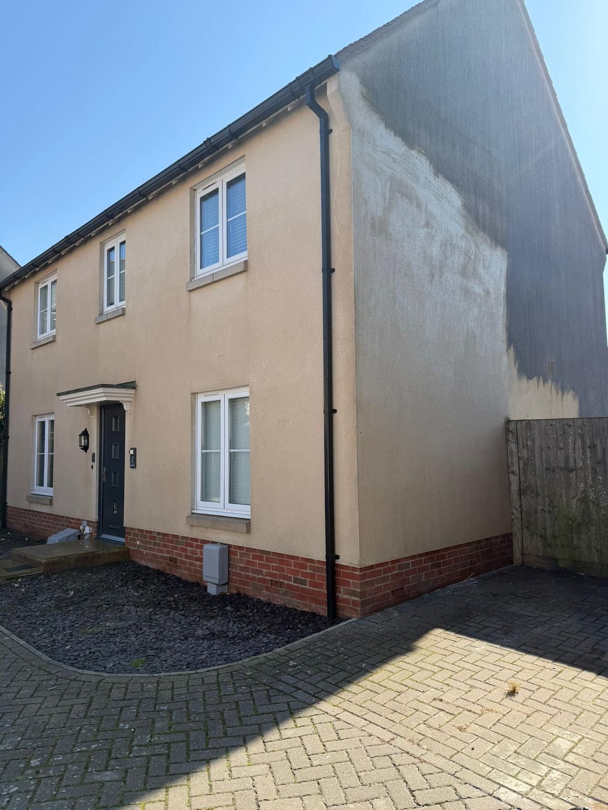 Home with dark algae on walls being cleaned with residential  soft wash render cleaning service