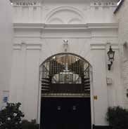 White building entrance with arched doorway and iron gate.