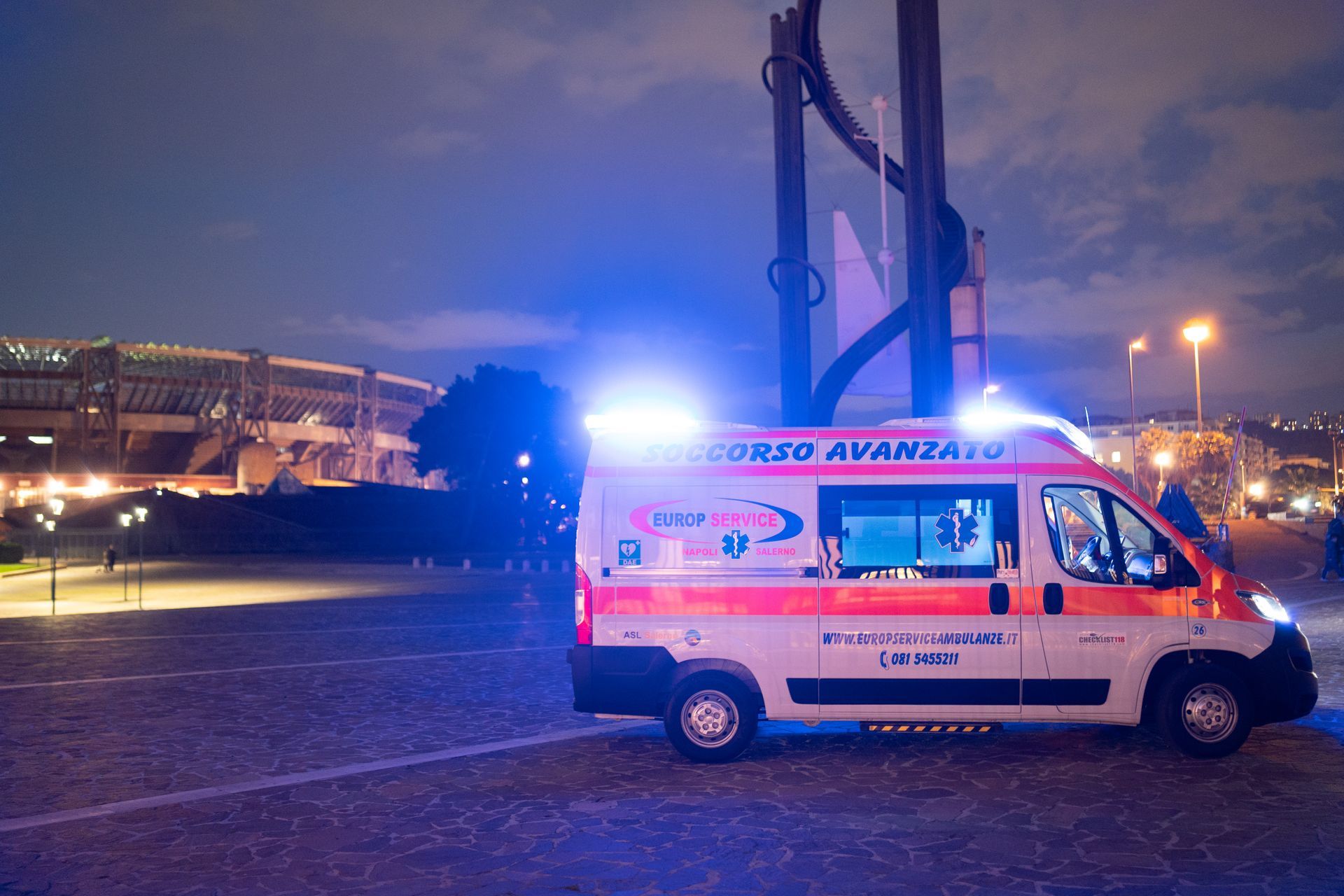 Ambulanza rossa con luci lampeggianti parcheggiata di notte in una strada cittadina