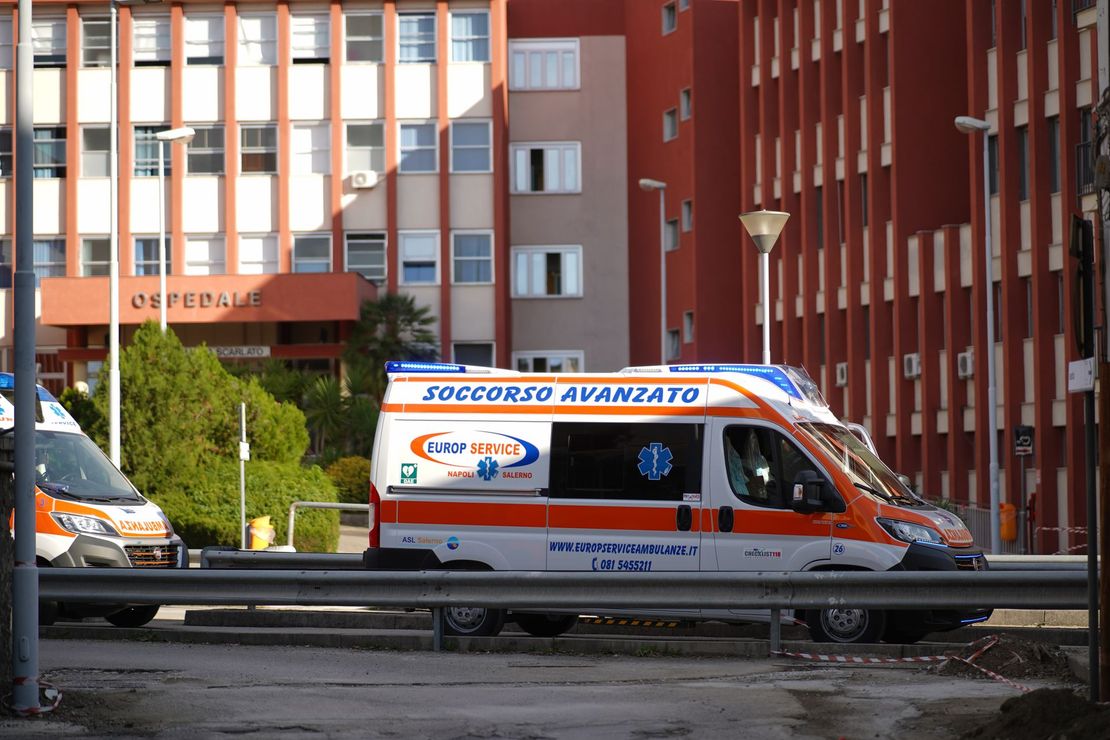 Ambulanza bianca e arancione parcheggiata su una strada di fronte a un edificio rosso