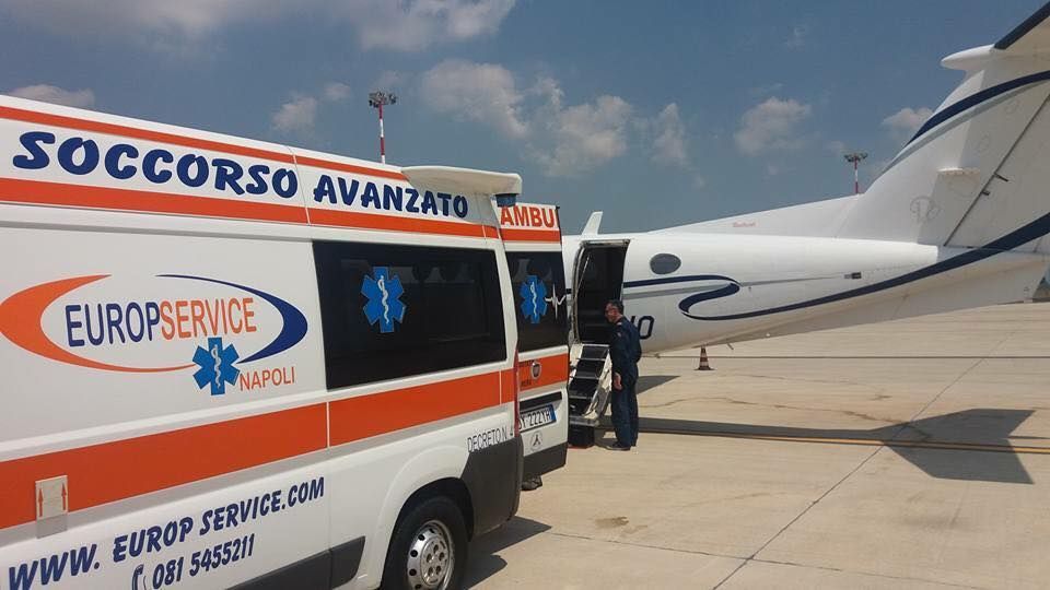 Un'ambulanza è parcheggiata accanto a un jet privato sulla pista di un aeroporto, con i soccorritori nelle vicinanze.