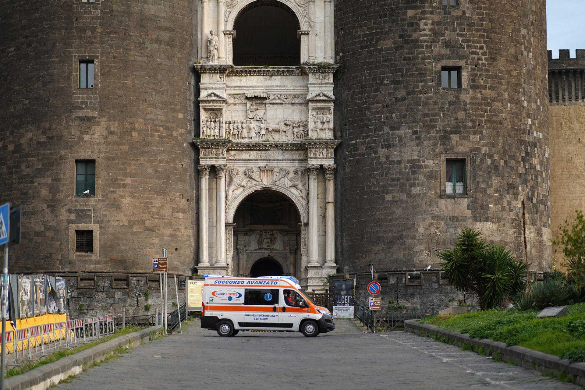 Ambulanza parcheggiata davanti a un cancello di pietra del castello con ingresso ad arco e ponte levatoio.