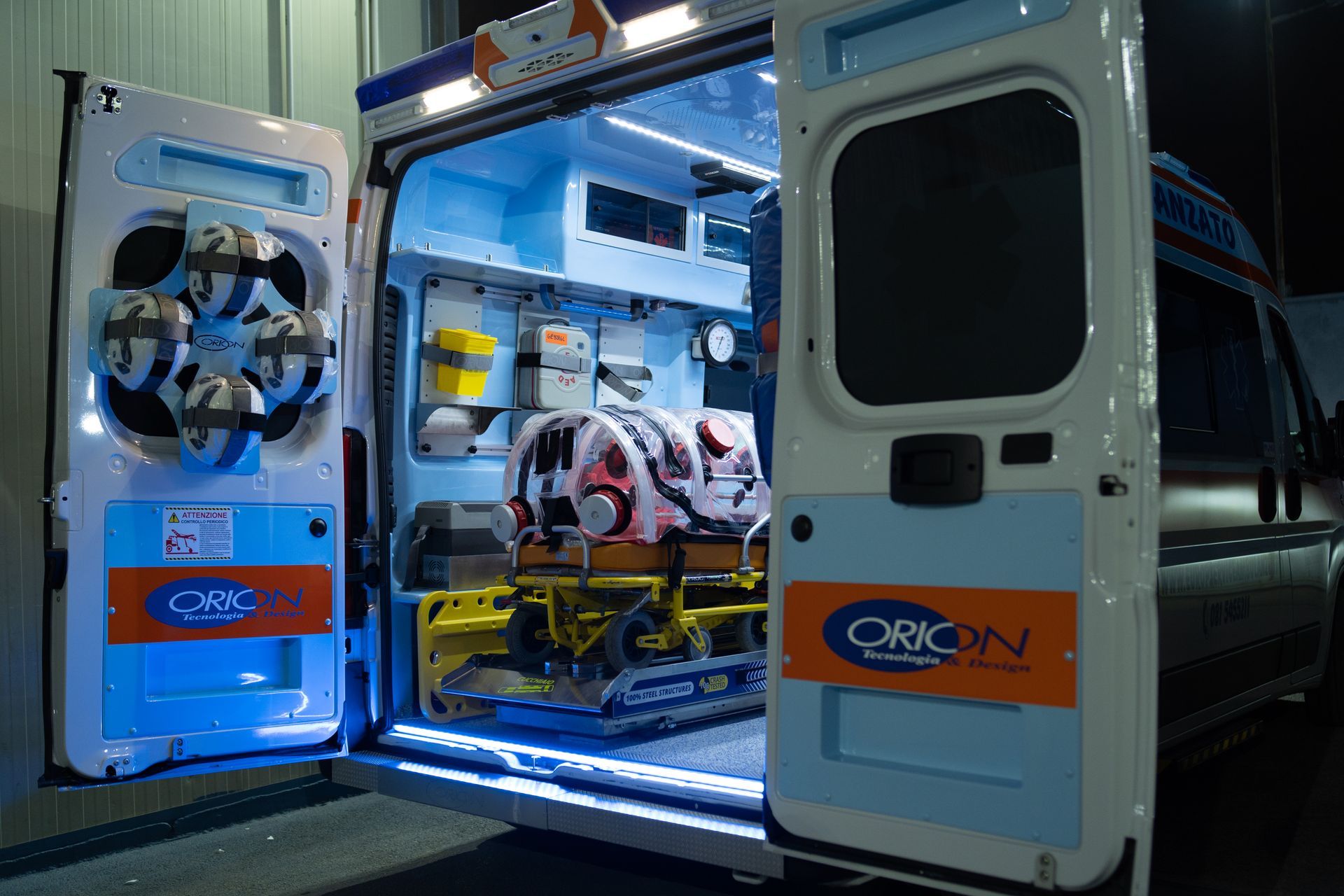 Ambulanza aperta con attrezzature mediche illuminate di blu all'interno e portelloni posteriori spalancati di notte