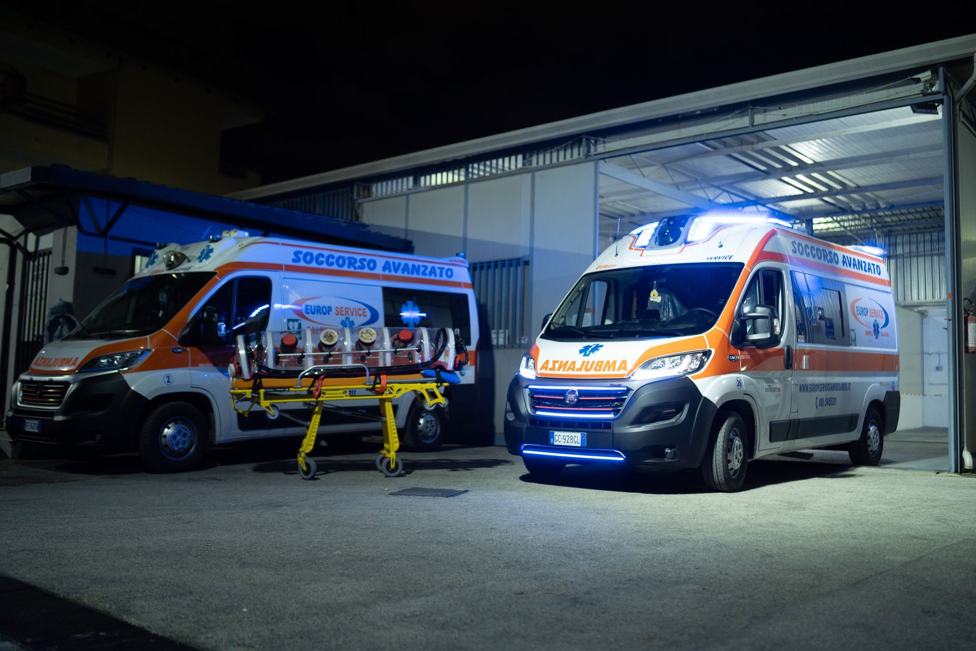 Di notte, due ambulanze arancioni e bianche erano parcheggiate fuori da un garage.