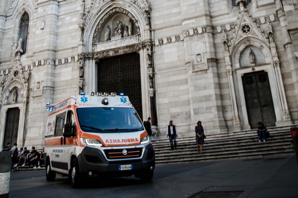 Un'ambulanza parcheggiata all'esterno dell'imponente ingresso di una cattedrale in pietra.