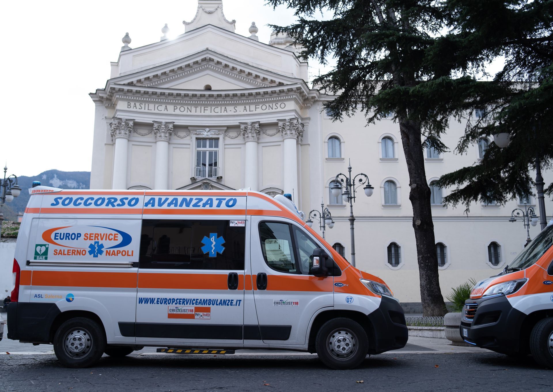 Ambulanze parcheggiate davanti a una chiesa bianca in una via della città.