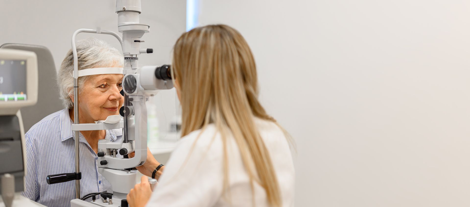 Eye exam in a clinic, with a patient in a slit lamp and an eye doctor examining her.