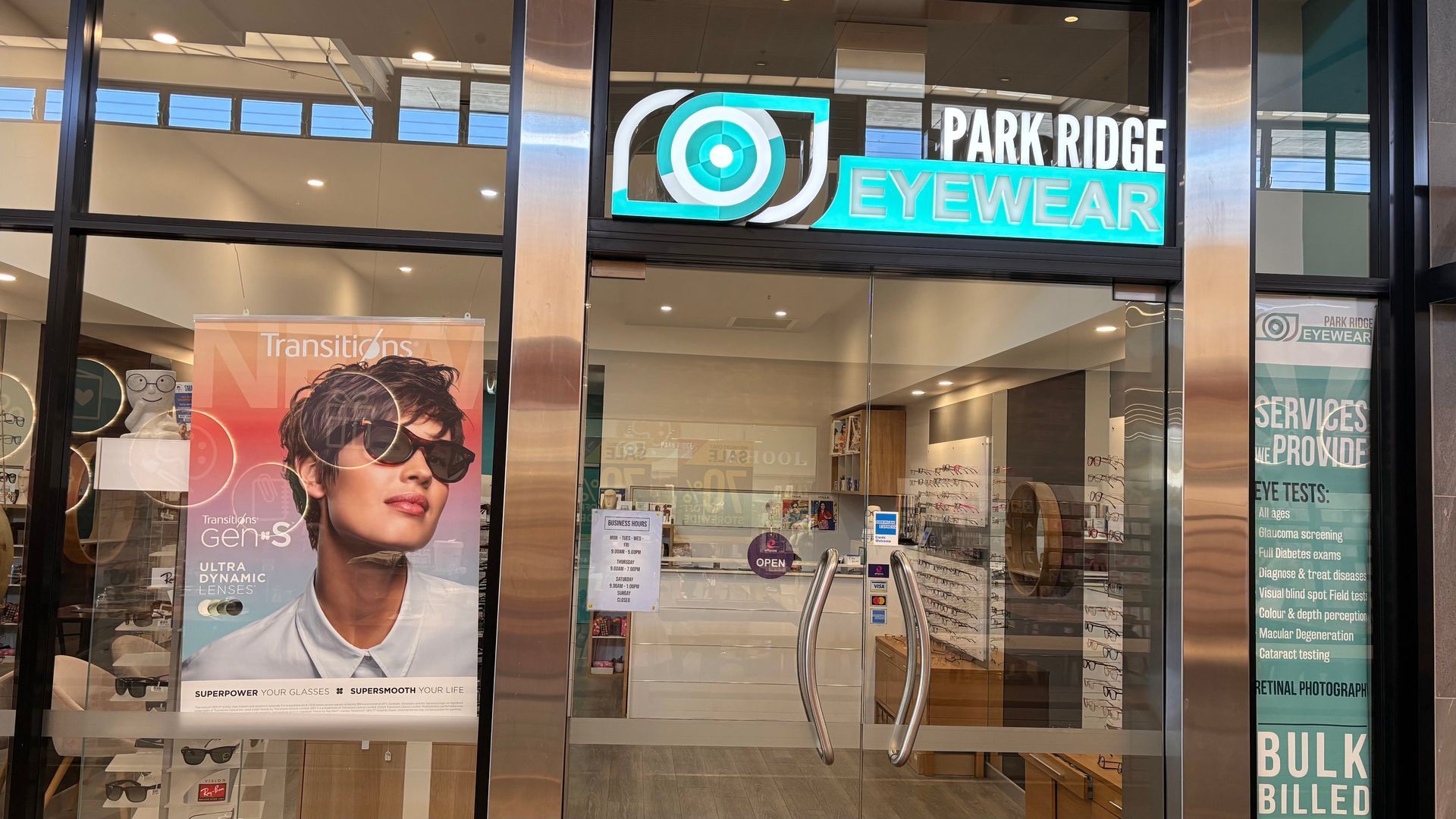 Storefront of Park Ridge Eyewear with illuminated sign and display posters behind glass doors
