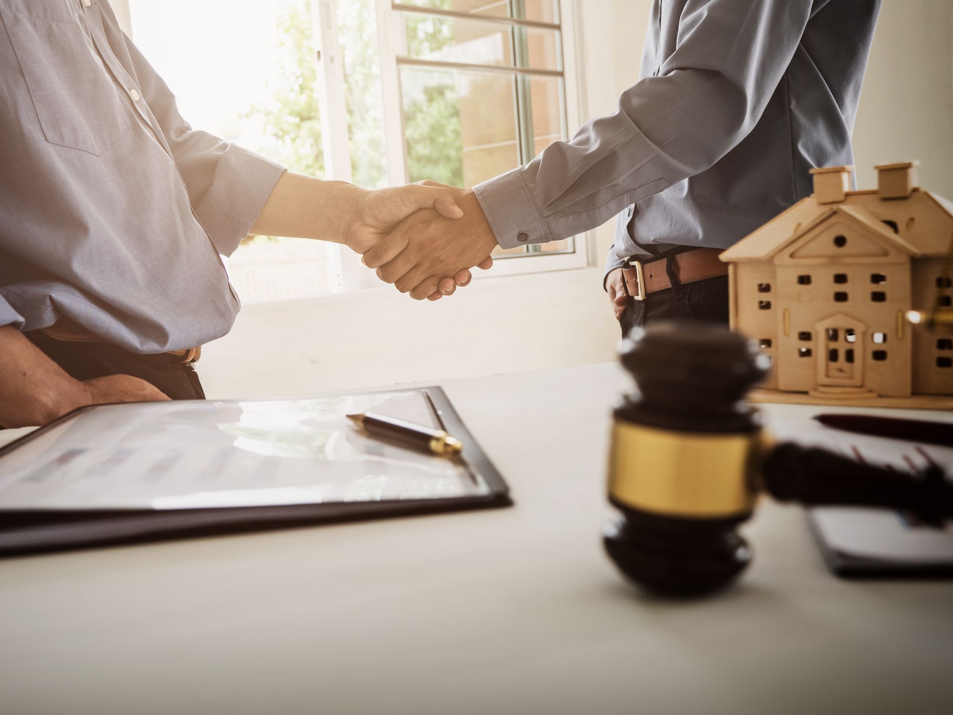 a wooden house is sitting on a wooden table next to a wooden gavel .