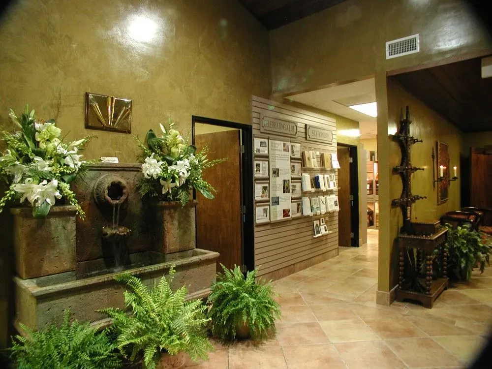 Hotel lobby with stone fountain, potted plants, and brochure rack under warm lighting