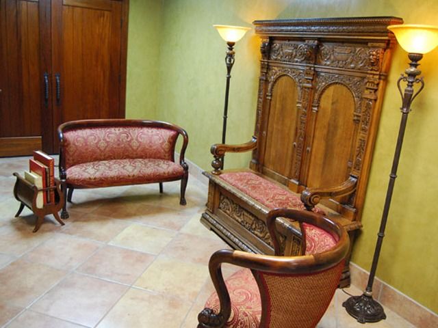 Elegant vintage waiting area with two patterned loveseats, wooden cabinet, and floor lamps on tiled floor