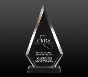 Glass trophy with CEDA and “Outstanding Funeral Home McKenzie Mortuary” on a dark background