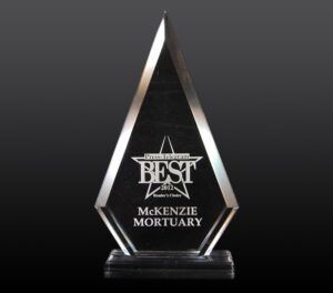 Clear glass award plaque with “Best” and “McKenzie Mortuary” engraved on a black base