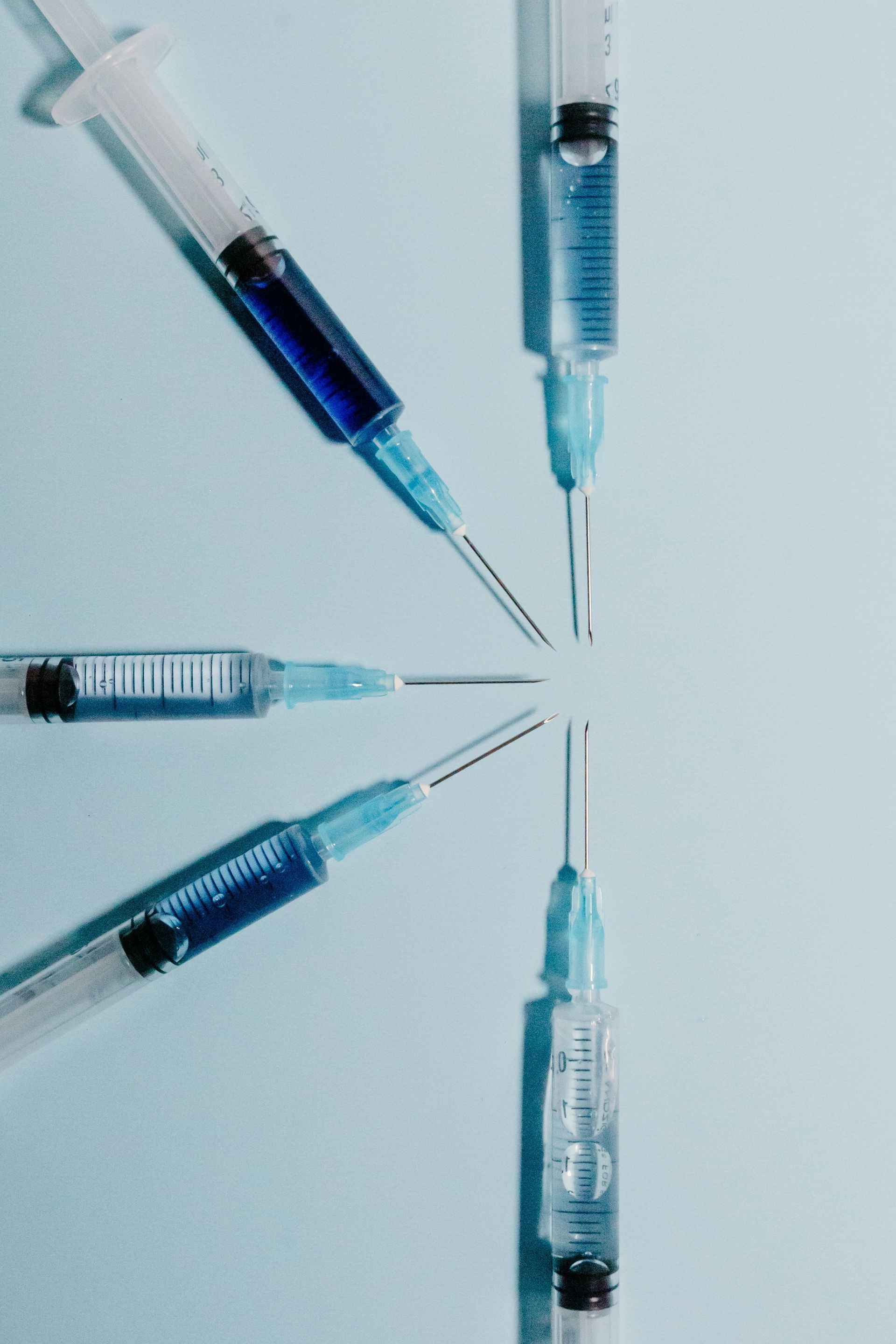 Scientist in lab coat uses dropper to add liquid to a test tube with green liquid.