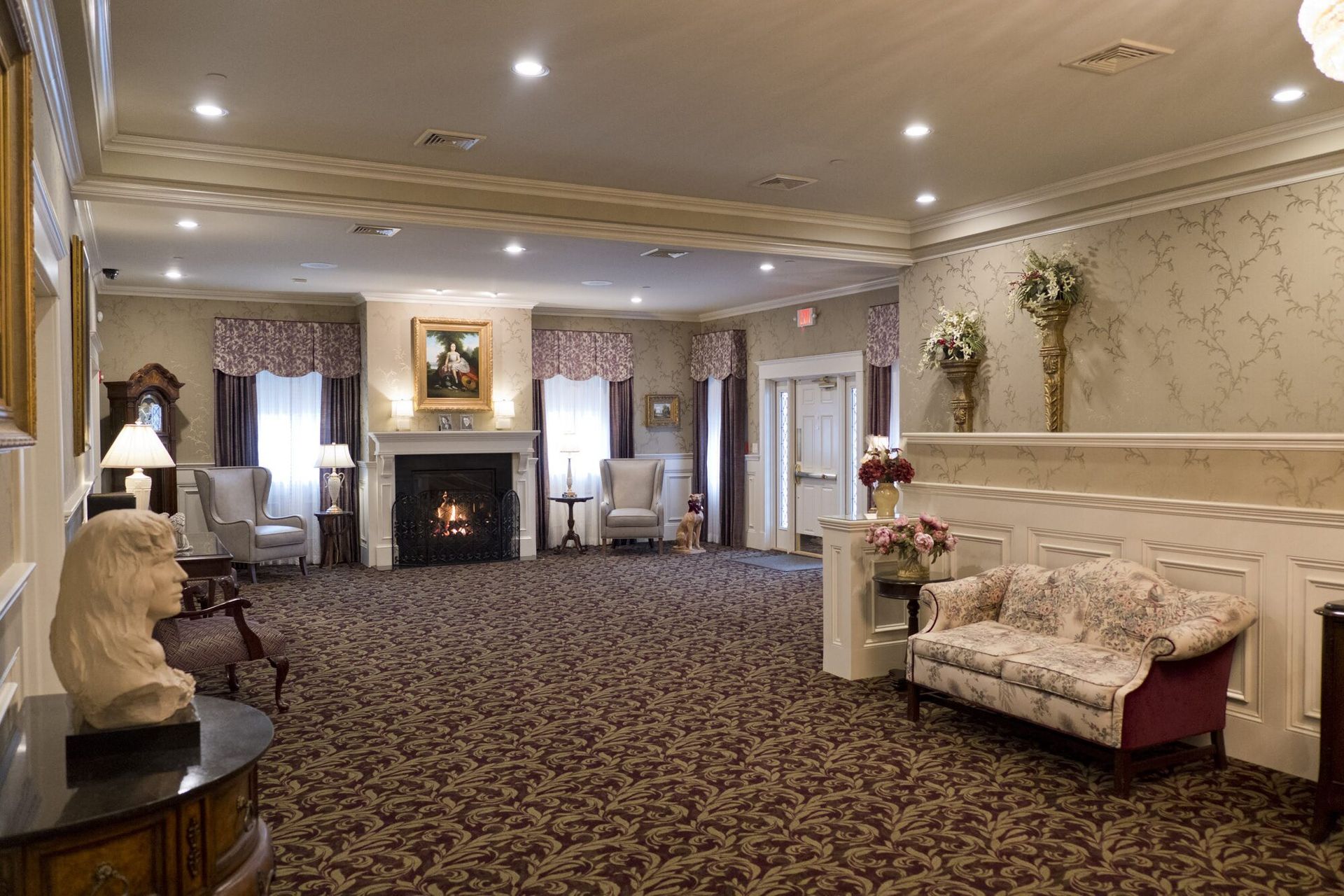 Spacious, carpeted room with fireplace, seating, and decorative accents. Likely a funeral home interior.