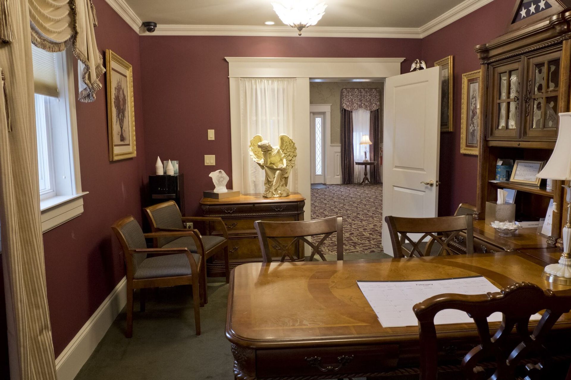 Formal office with mahogany furniture, burgundy walls, and an antique vibe.