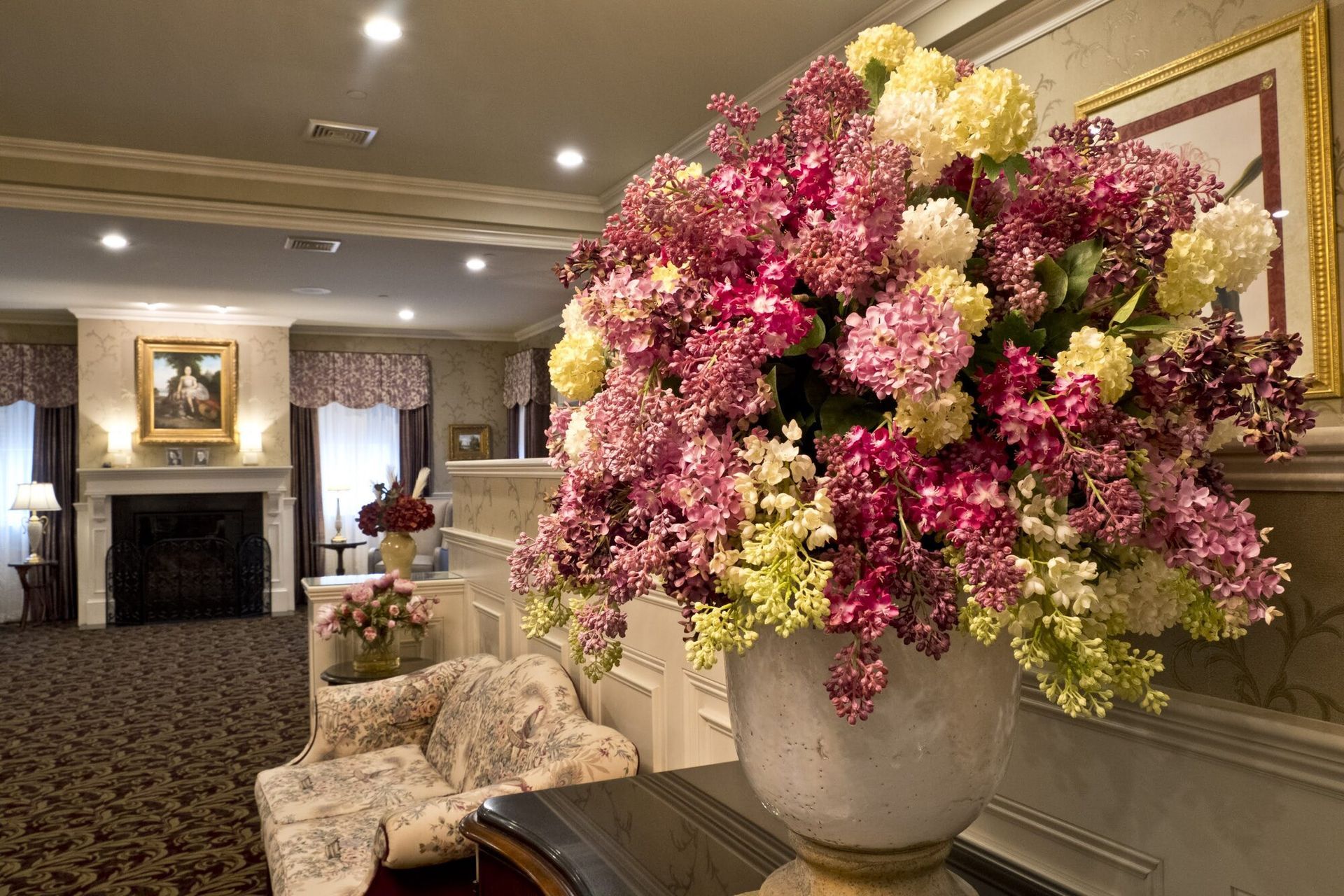 Large flower arrangement in a vase, in a room with a fireplace and ornate details.