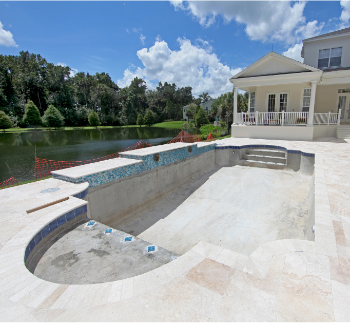 An empty swimming pool with a house in the background