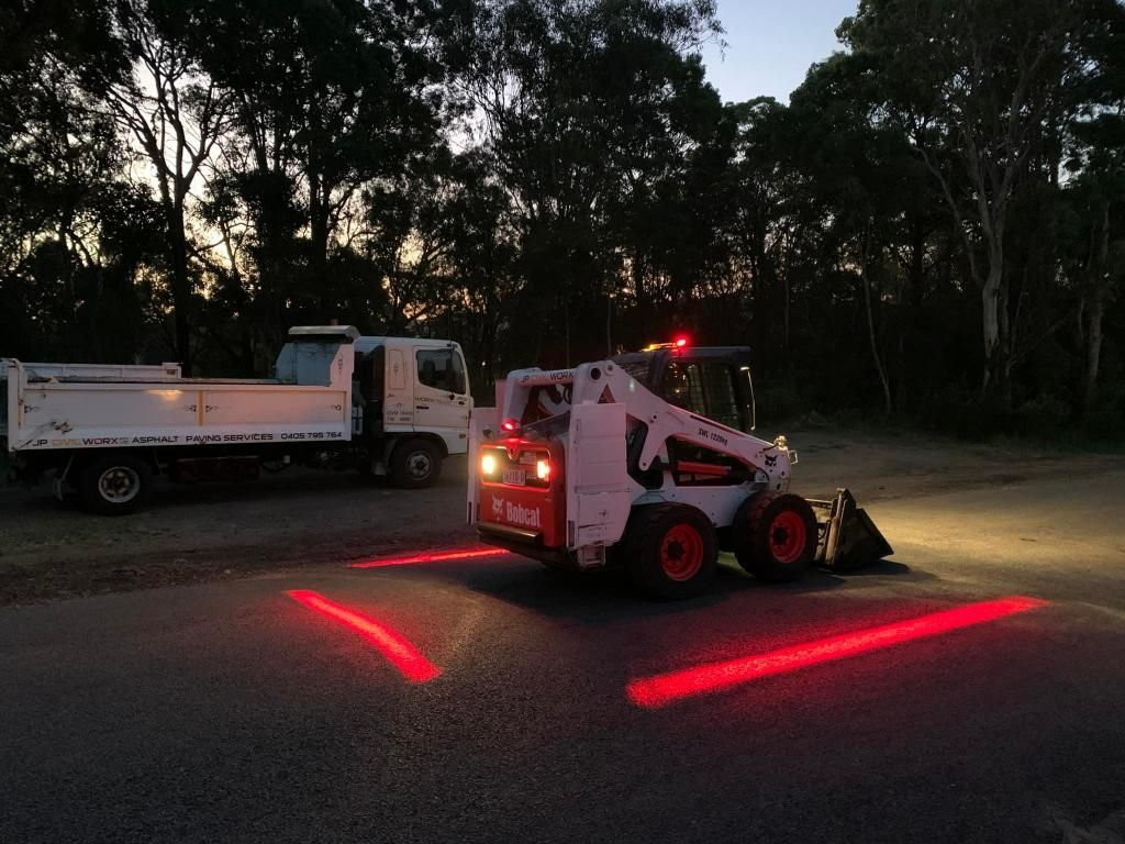 Bobcat Tractor is Driving Down a Road at Night — JP Civilworx Pty Ltd in Cessnock, NSW