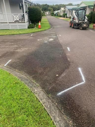 Bulldozer is Driving Down a Street Next to a House — JP Civilworx Pty Ltd in Port Macquarie, NSW
