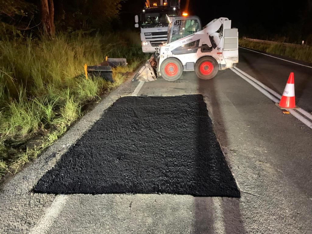 Bobcat is Laying Asphalt on the Side of a Road at Night — JP Civilworx Pty Ltd in Taree, NSW