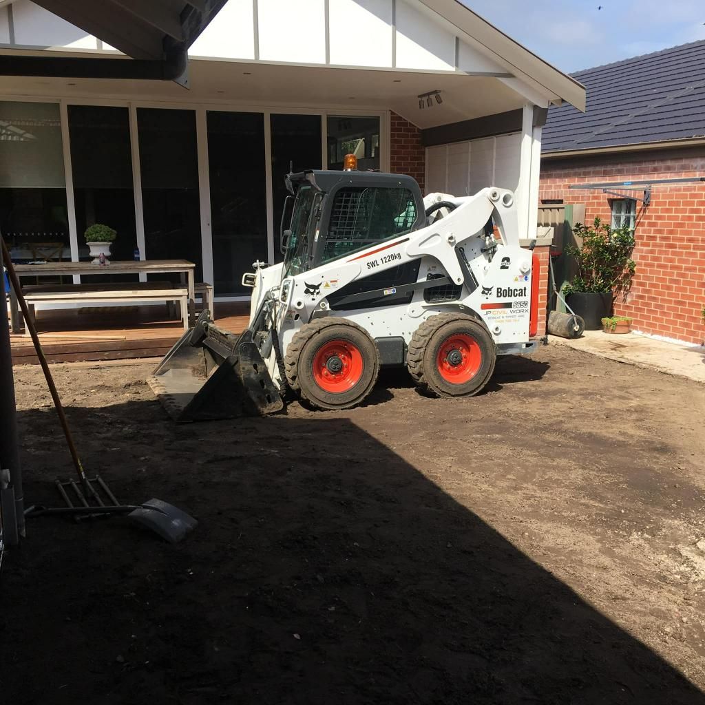 Bobcat Tractor is Parked in Front of a Brick House — JP Civilworx Pty Ltd in Cessnock, NSW