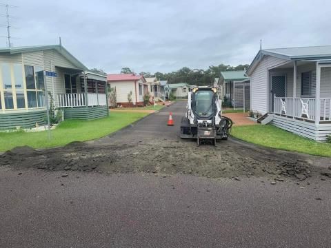 Bulldozer is Driving Down a Dirt Road in a Mobile Home Park — JP Civilworx Pty Ltd in Mid North Coast, NSW