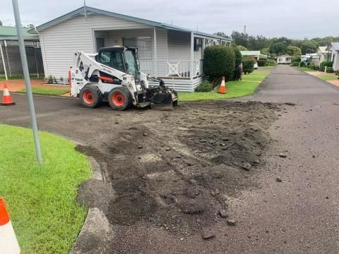 Bobcat is Sitting on the Side of a Road in Front of a House — JP Civilworx Pty Ltd in Maitland, NSW