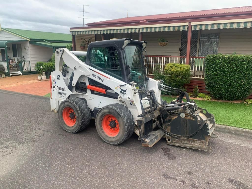 Bobcat is Parked on the Side of the Road in Front of a House — JP Civilworx Pty Ltd in Taree, NSW