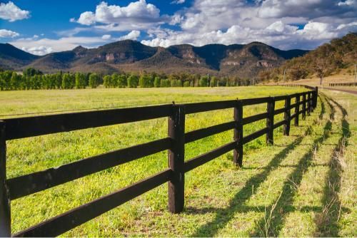 Wooden Fence Surrounds a Grassy Field With Mountains — JP Civilworx Pty Ltd in Muswellbrook, NSW