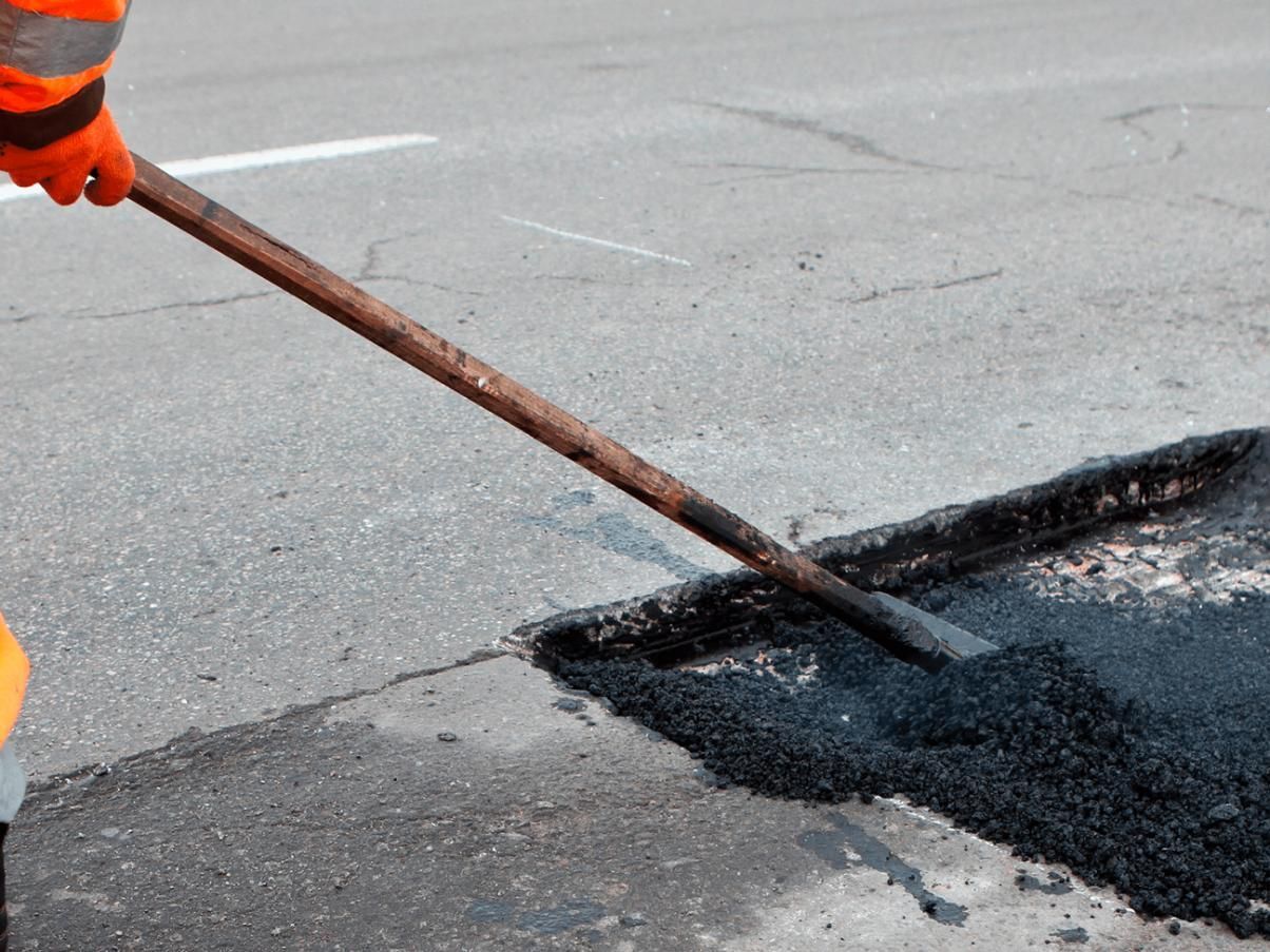 Person is Spreading Asphalt on a Road With a Shovel — JP Civilworx Pty Ltd in Taree, NSW