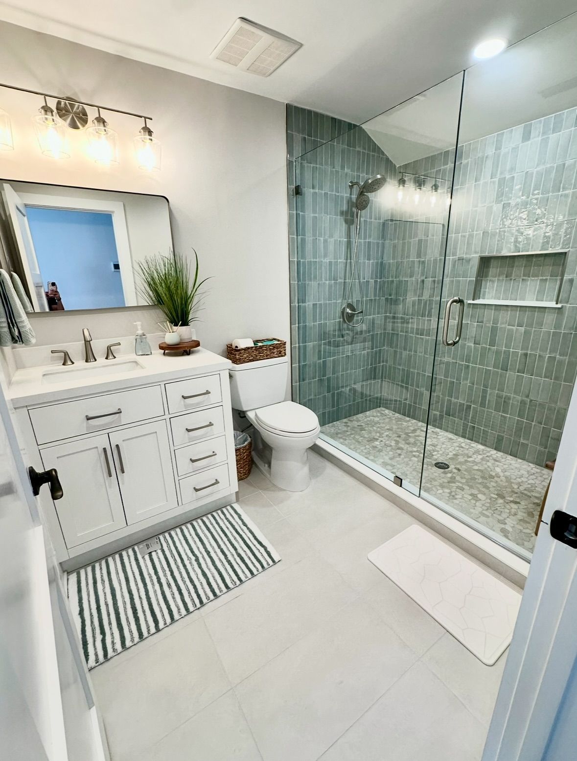 Glass shower with blue and white mosaic tile walls.
