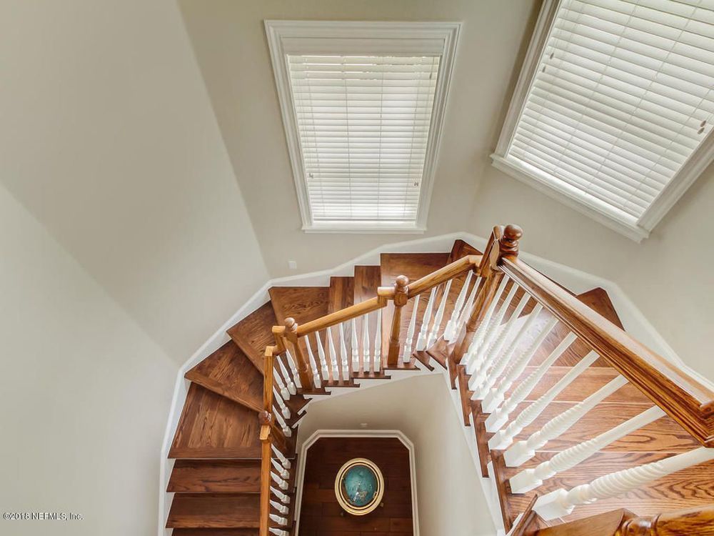 Wooden staircase with white railing, ascending from bottom center, with two windows above.