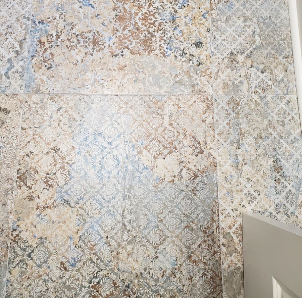Textured tile flooring with faded blue, beige, and brown patterns.