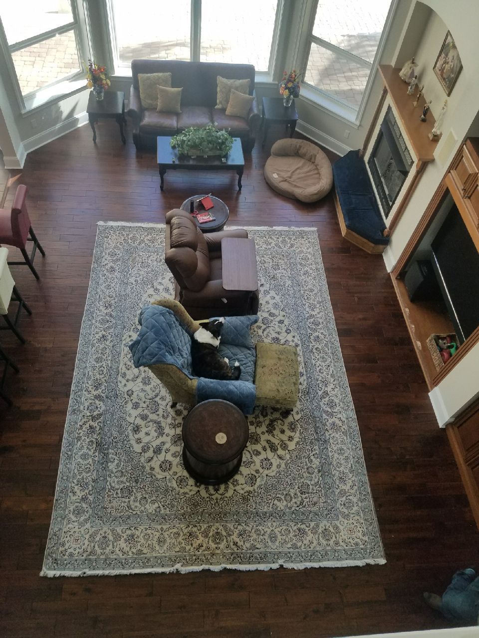 Living room with dark wood floors, a large patterned rug, furniture, and a fireplace.