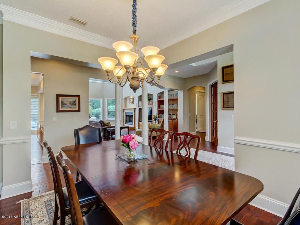 Formal dining room with wooden table, chandelier, and arched entryway.