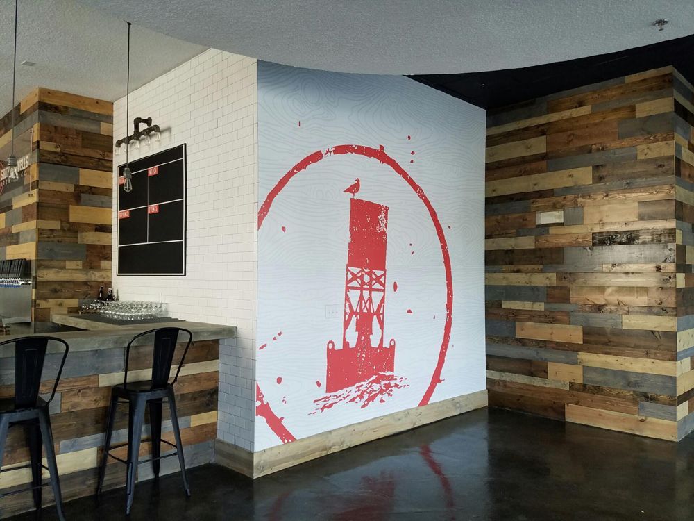 Interior of a business with a lighthouse logo on the wall. Wood paneling and bar stools.