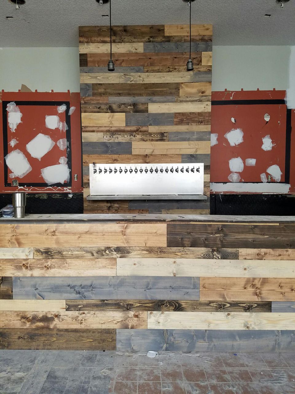 Bar under construction with wood paneling, stainless steel taps, and exposed wall areas.